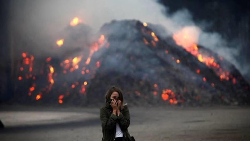 Una dona es protegeix del fum, ben a prop de les flames