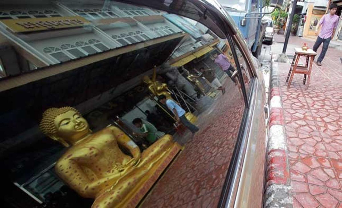 Un treballador tailandès es reflecteix en el vidre de la finestra d’un cotxe a Bangkok.