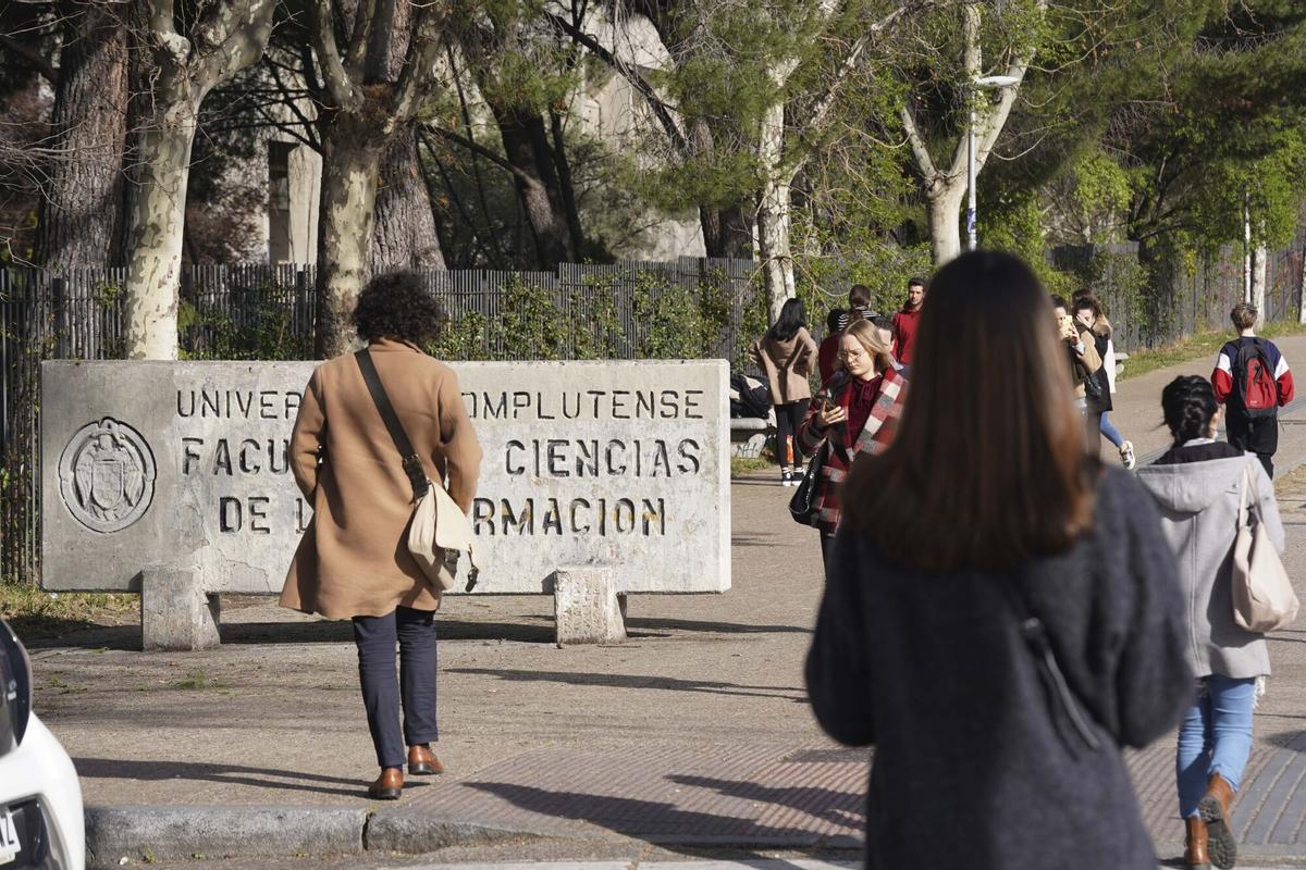 Estudiantes caminan ante el cartel de la Facultad de Ciencia de la Información de la Universidad Complutense de Madrid.