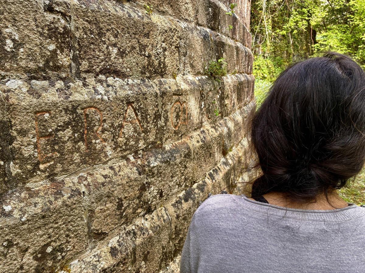 Una mujer observa la inscripción, coloreada de naranja.