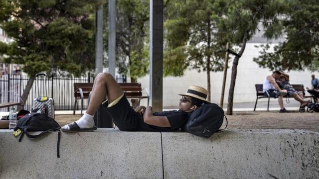 Un hombre duerme al lago de una botella de agua durante la calima en el Parc dels Ocells de L'Hospitalet de Llobregat.