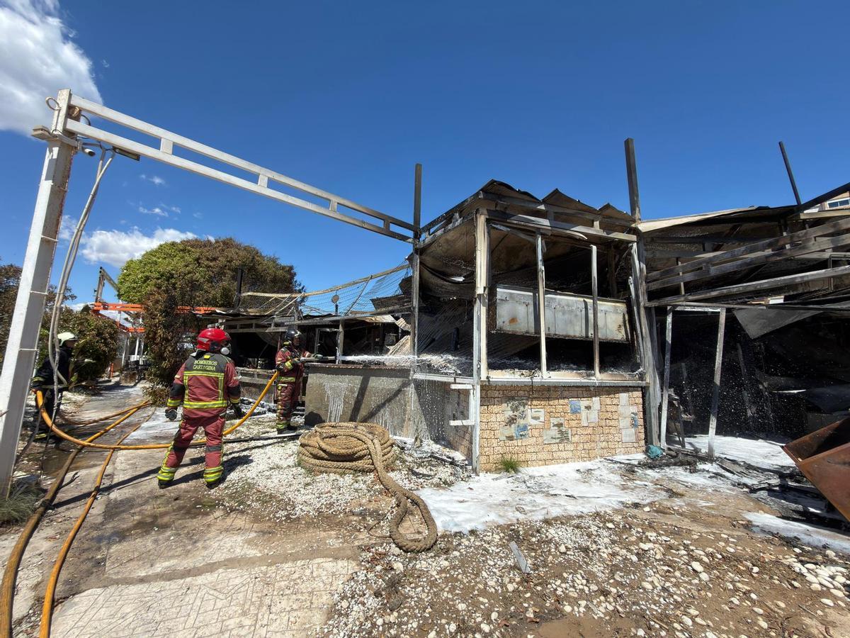 Bomberos trabajan en el incendio del restaurante en La Manga, que ha quedado completamente calcinado.