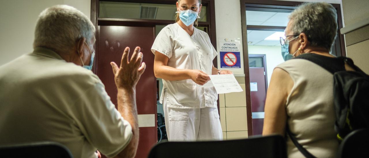 Una sanitaria atiende a una pareja de personas mayores en un centro de salud.