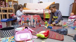 Júlia y Martí, de cinco años, con sus juguetes en el salón de su casa.