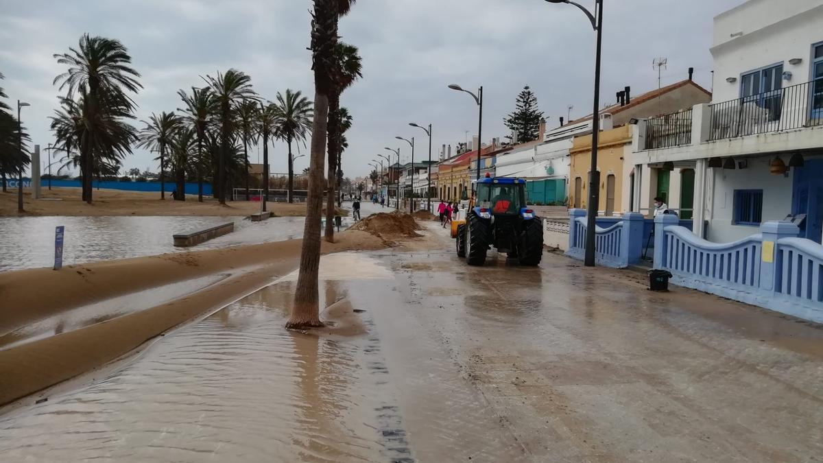 Un tractor limpiando de arena el paseo de La Patacona tras el temporal.