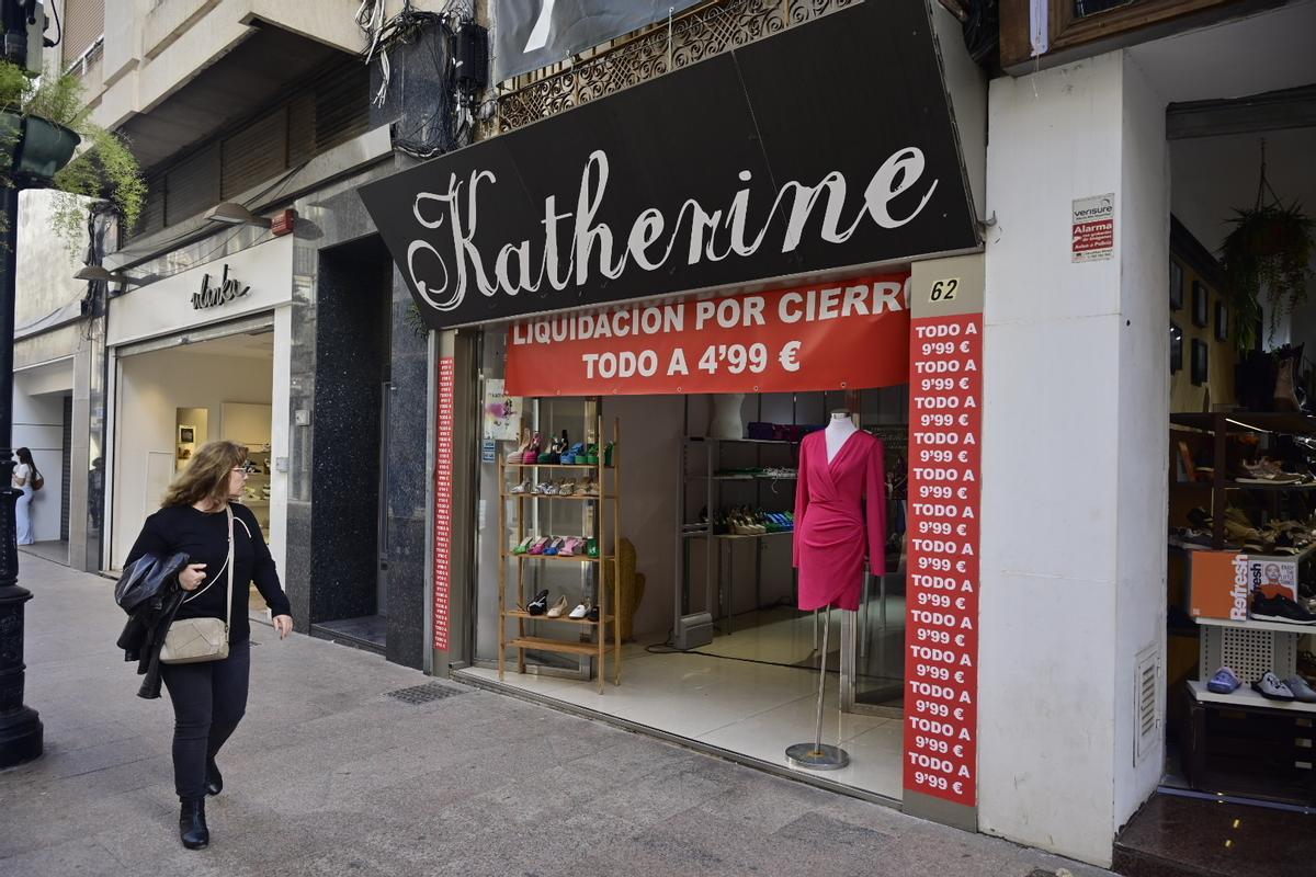 Un mujer pasa frente a un comercio del centro de Castellón que liquida por cierre.