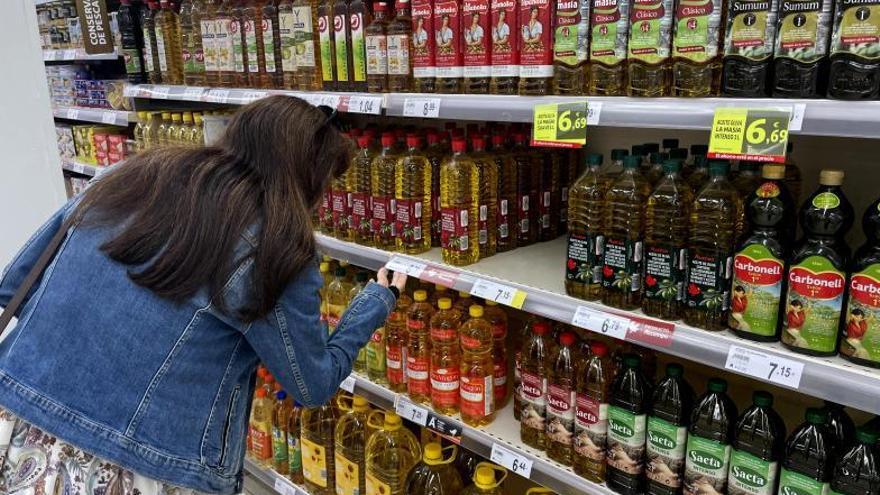 Una mujer compara precios de diferentes aceites en un supermercado. | MIGUEL ÁNGEL GRACIA