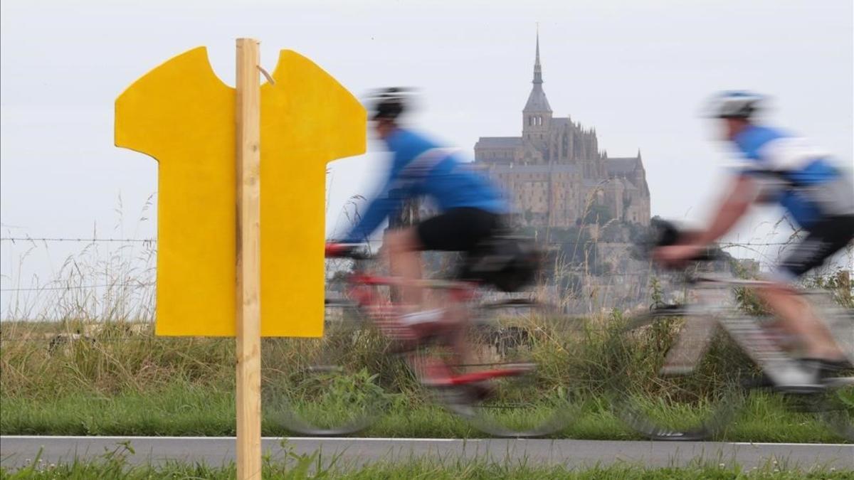 Uno ciclistas pasan cerca del Mont de Saint Michel, donde el sábado comienza el Tour