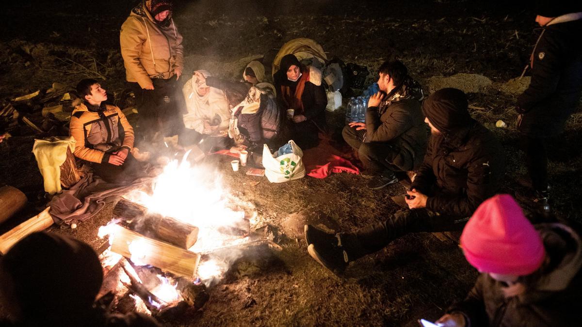 Ciutadans ucraïnesos s'escalfen al costat d'una foguera després d'arribar a Polònia