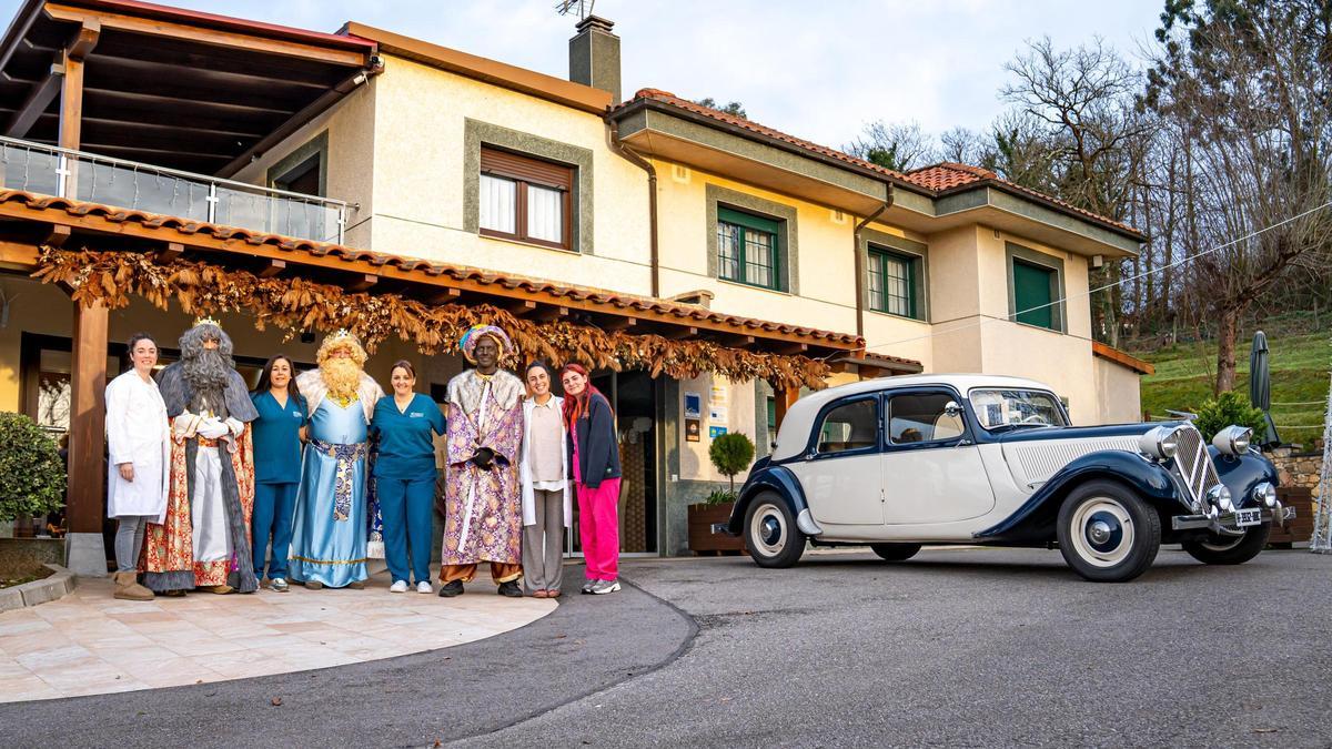 El personal con los Reyes Magos y, al fondo, el vehículo clásico.