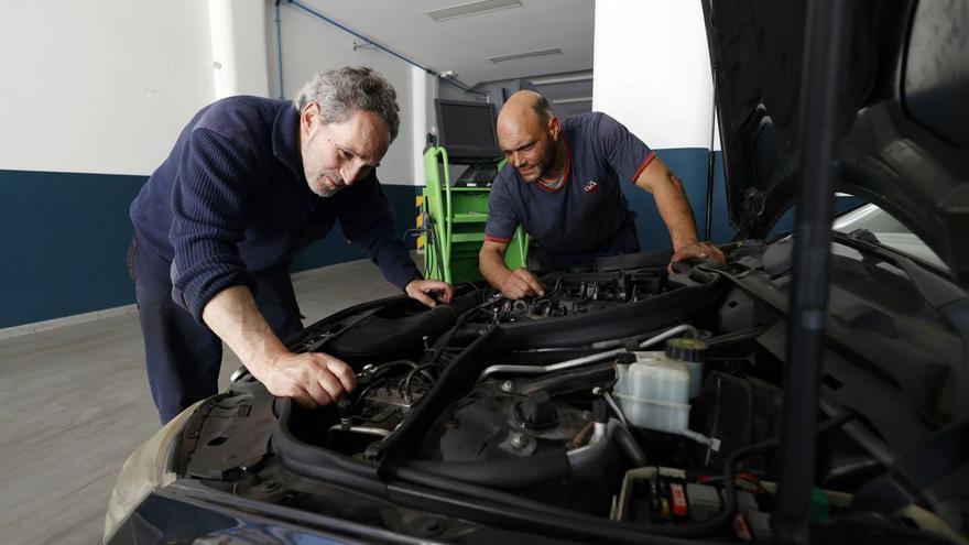 Toño Rodríguez y uno de sus trabajadores revisan un coche en Talleres Porteliña.