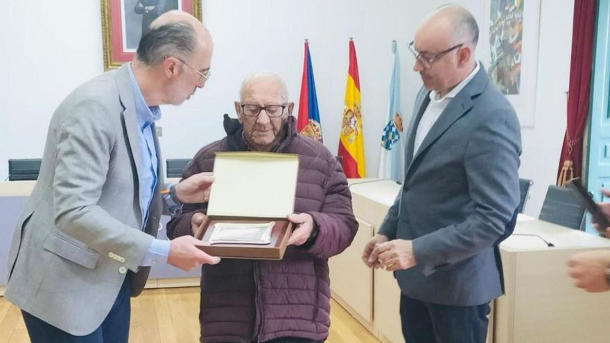 José Trigo recibe de manos del alcalde, Jesús Vázquez Almuiña, la metopa de  reconocimiento.