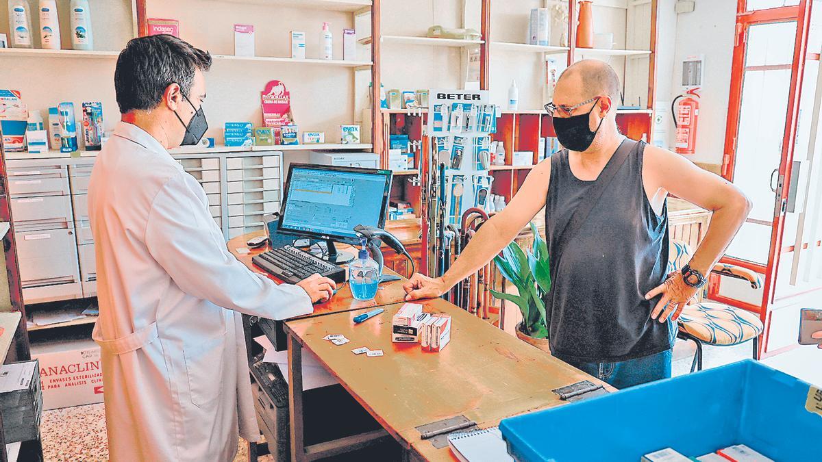 José Ramón García (izquierda) atiende  en su farmacia rural en Casas Altas, en el  Rincón de Ademuz.