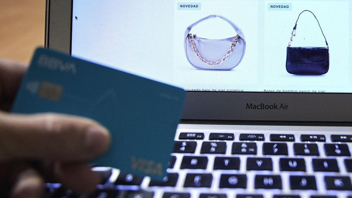 Una persona, tarjeta en mano, se dispone a comprar un bolso por Internet en la era del repunte del ciberdelito.