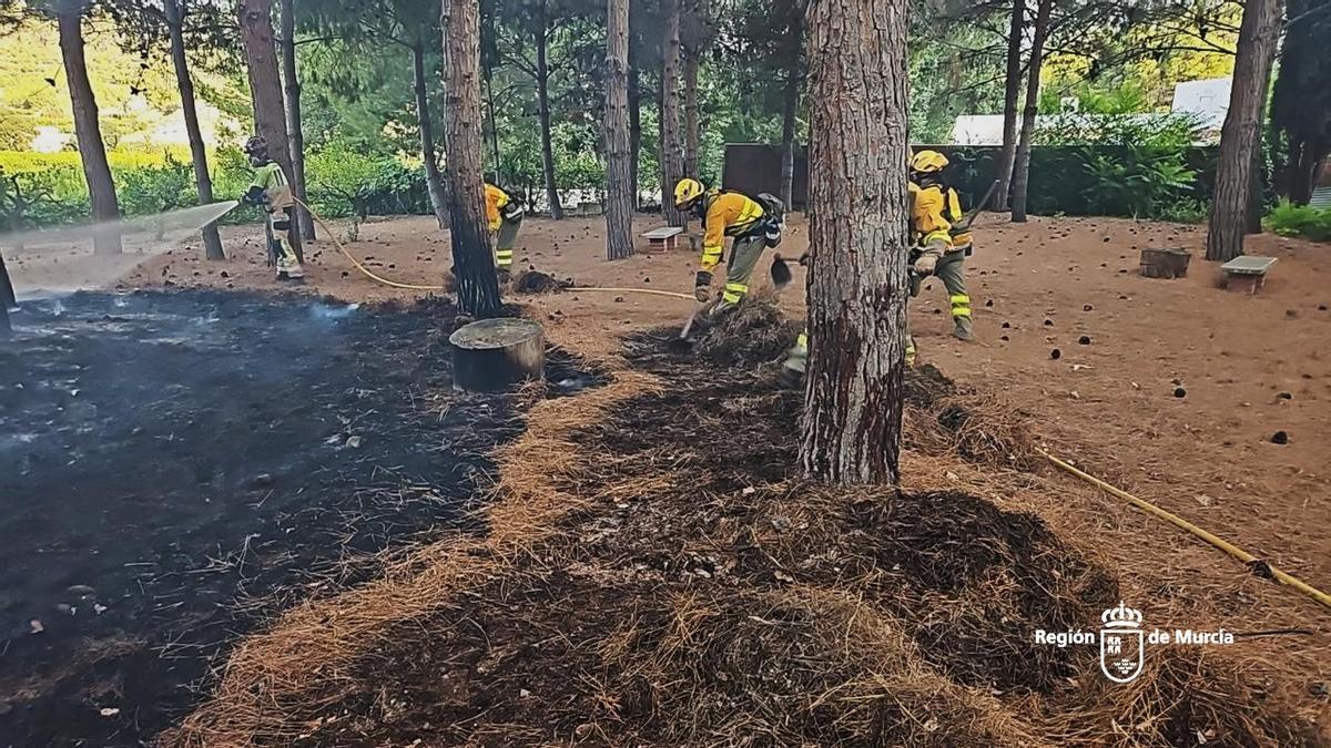Los bomberos trabajan sobre el terreno quemado por el incendio.