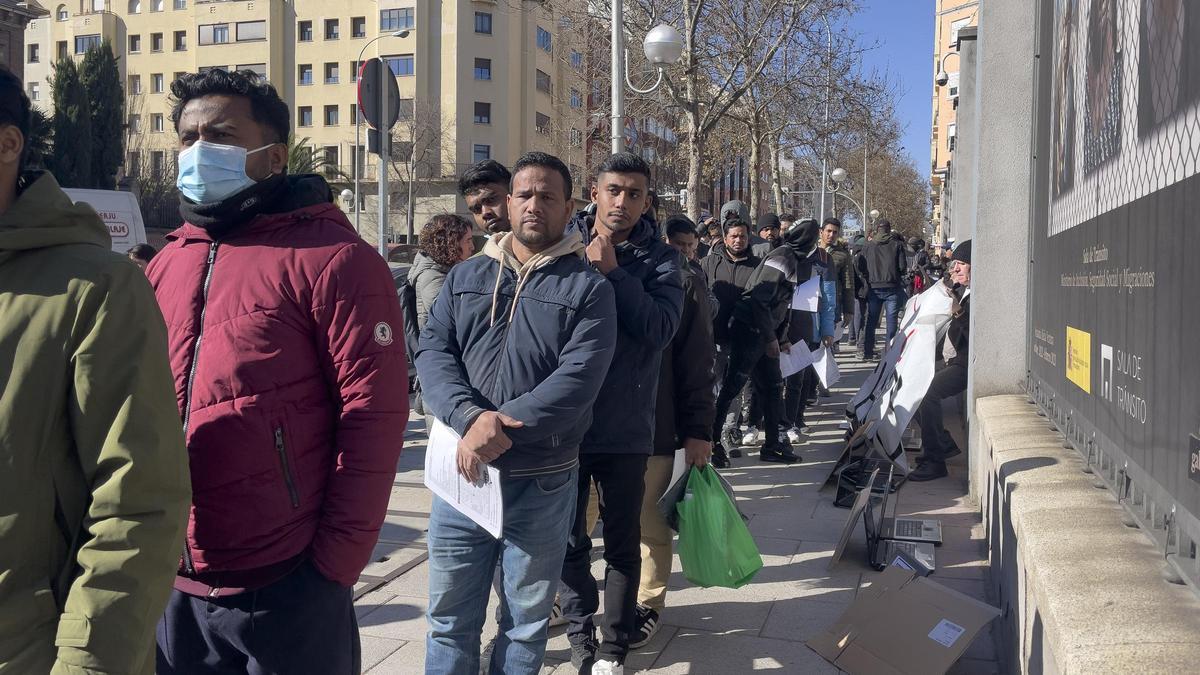 Migrantes hacen cola frente al Ministerio de Inclusión, Seguridad Social y Migraciones en Madrid.