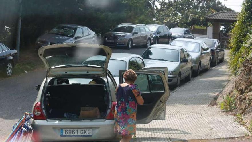 Una calle de Luanco con vehículos aparcados a ambos lados de la calzada.