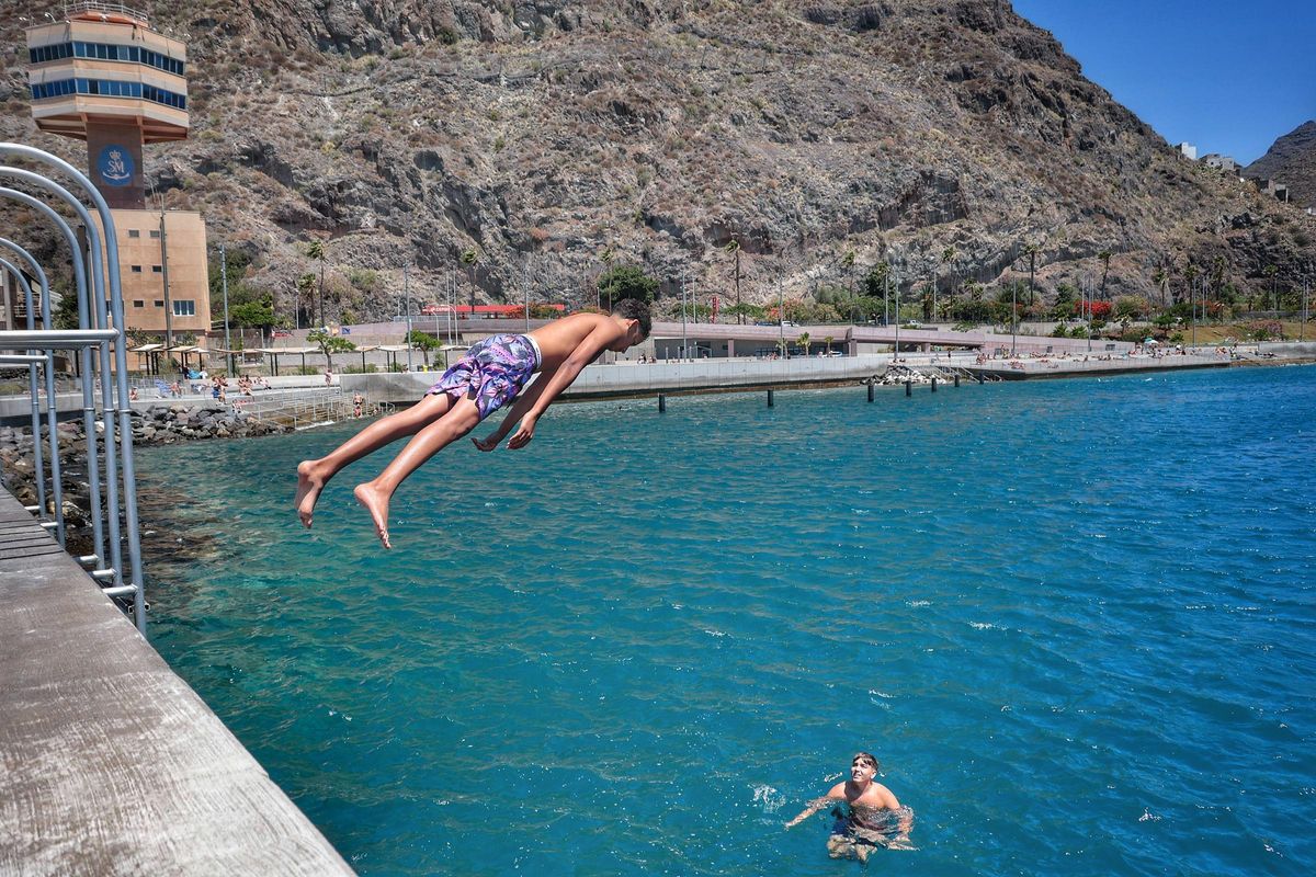 Young people jump into the sea from one of the walls in the puddle area.