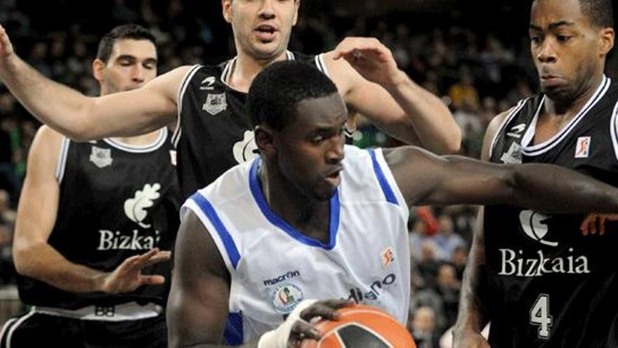 El pívot senegalés del Meridiano Alicante, Pape Sow (c), intenta un pase ante el alero estadounidense del Bizkaia Bilbao Basket Chris Warren (d), durante el encuentro correspondiente a la sexta jornada de la liga ACB de baloncesto disputado hoy en el Bizkaia Arena.