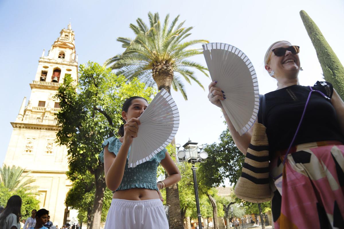 Turistas se abanican en el Patio de los Naranjos.