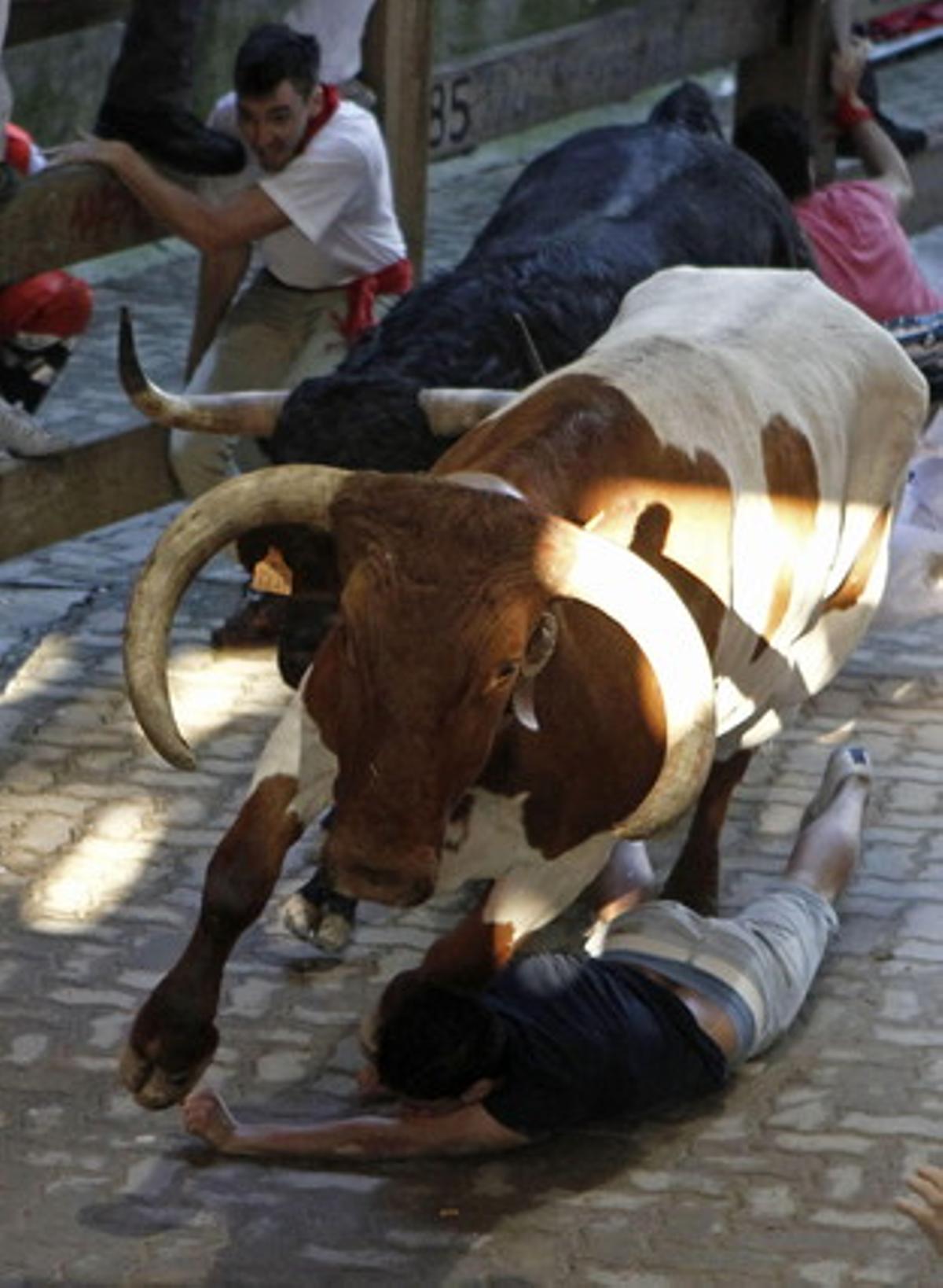 Un mosso en dificultats al caure davant un mans i un dels toros.