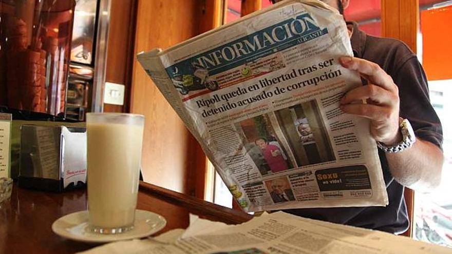 Imágenes de varias personas, la de la derecha vestida con la camiseta de la selección española de fútbol, leyendo ayer el periódico