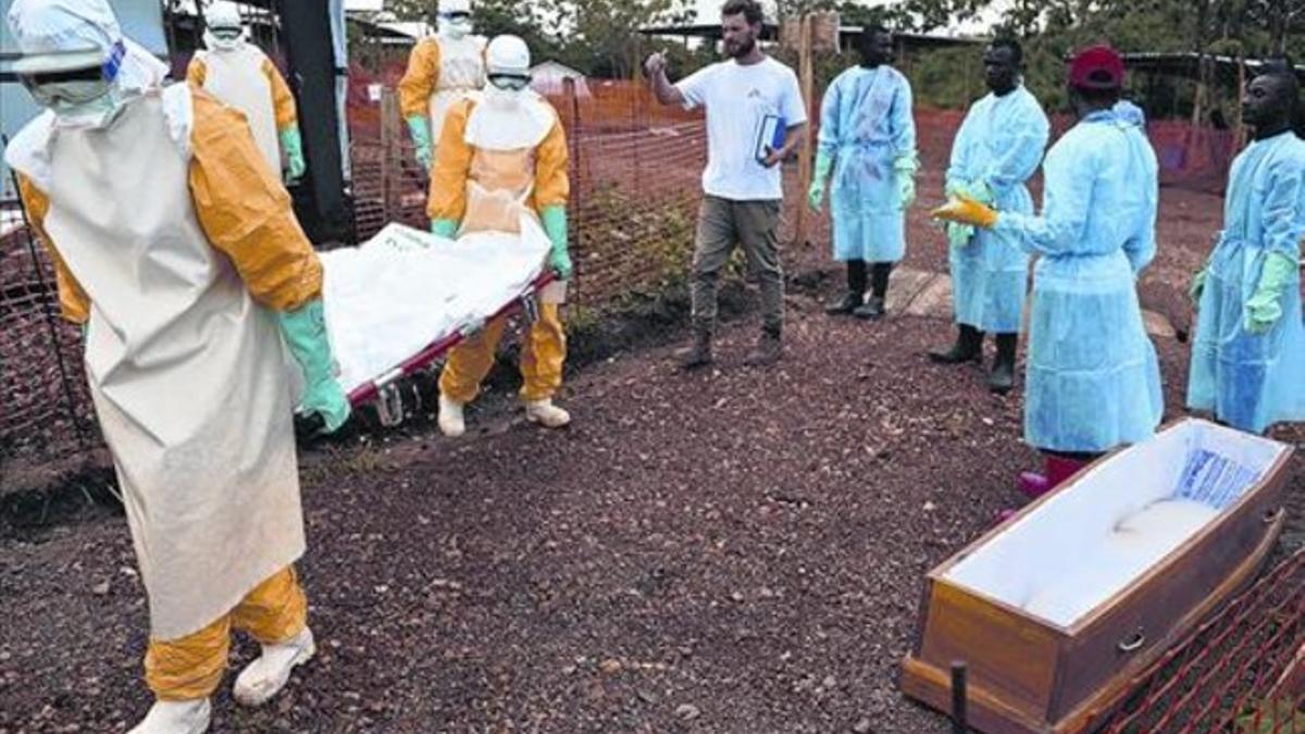 Personal médico con traje protector transporta el cadáver de una víctima del ébola en Kailahun, Sierra Leona.
