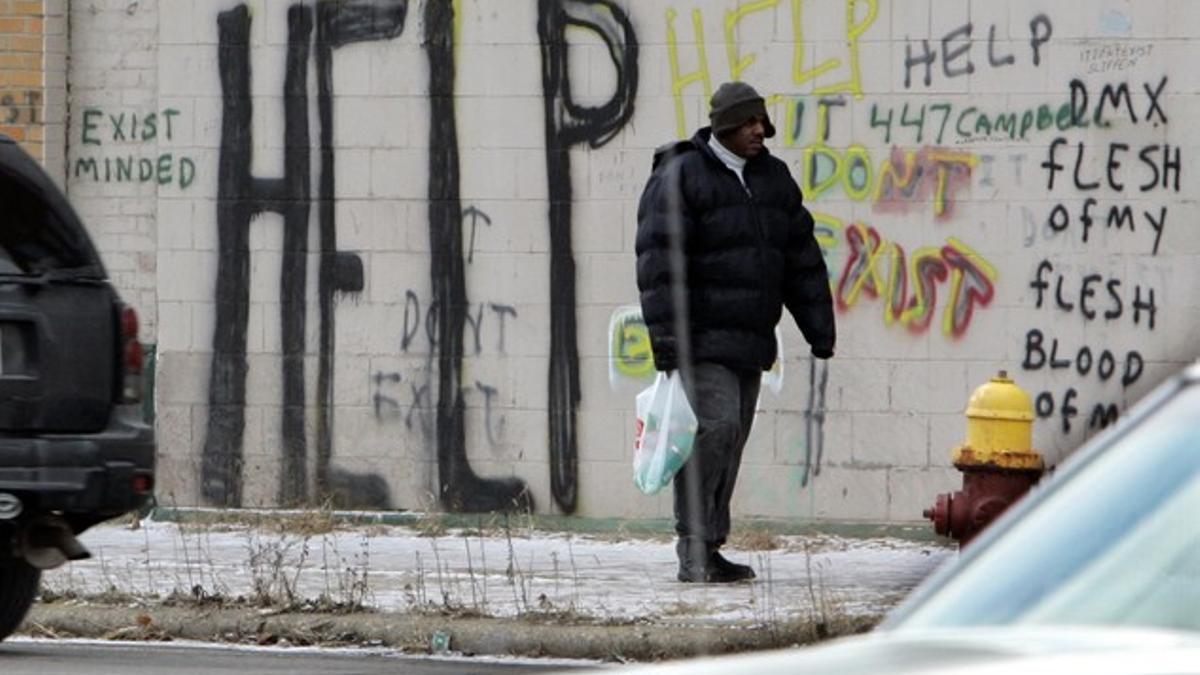 Un hombre pasa por delante de un grafiti con la palabra 'Help' (ayuda), en el centro de Detroit.