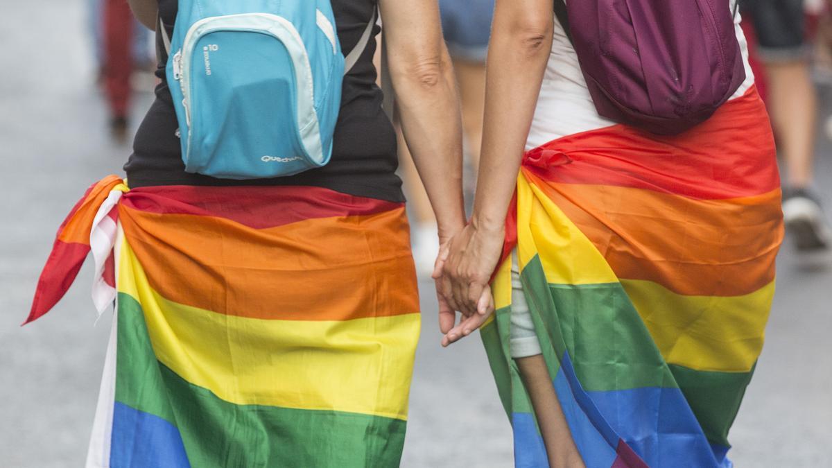 Dos personas dándose la mano durante uno de los desfiles por el día del Orgullo LGTBIQ