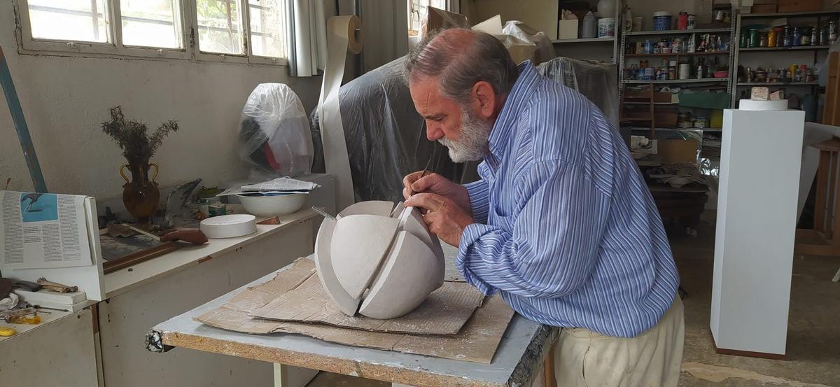 El escultor da forma a una de sus obras en el taller.