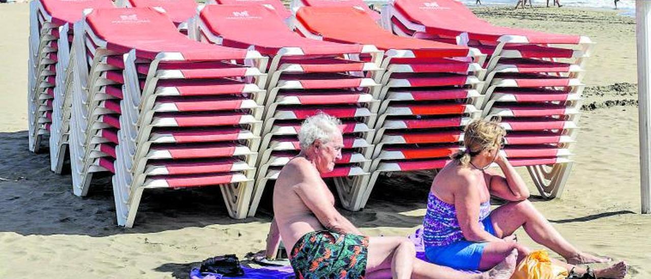 Dos turistas extranjeros toman el sol junto a unas hamacas en Canarias. | |