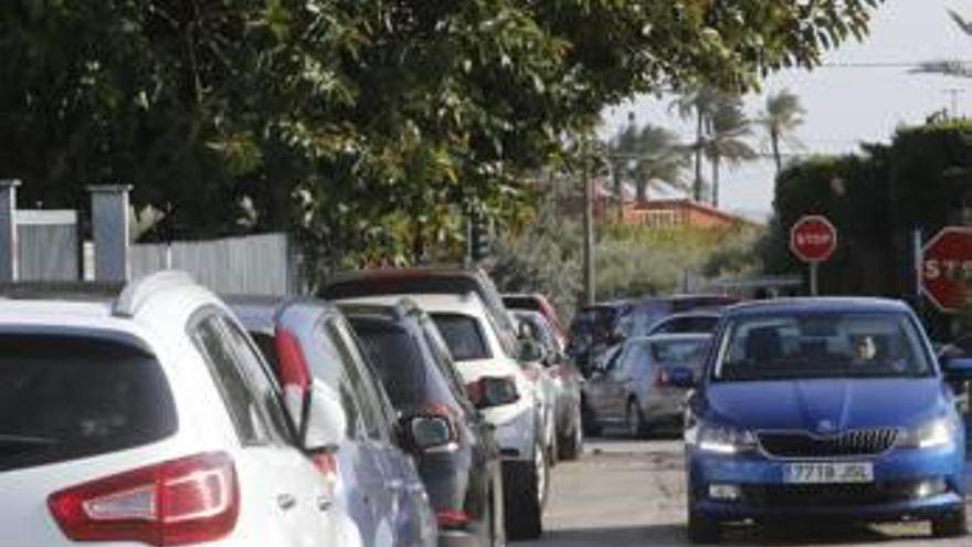 Coches mal aparcados en un camino que rodea al colegio, limitando la circulación a un carril, y multitud de coches de padres a la salida del colegio ayer.