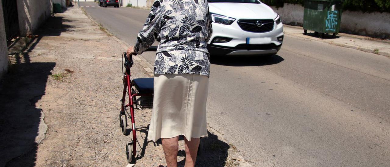 Una vecina con andador, en una acera de la Canyada. A la derecha, una calle de la urbanización el Pinar de Picassent. | AVUC/ L-EMV