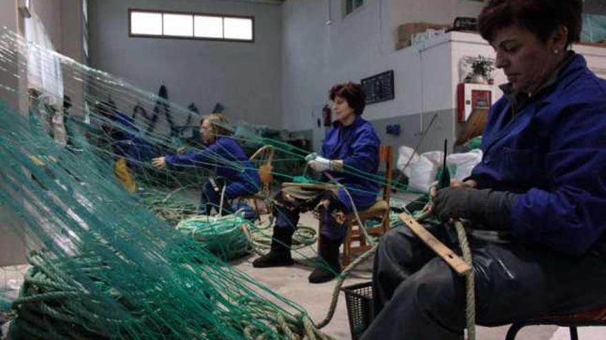 Un grupo de redeiras en la nave del recinto del puerto guardés, realizando su trabajo.  // J. Lores