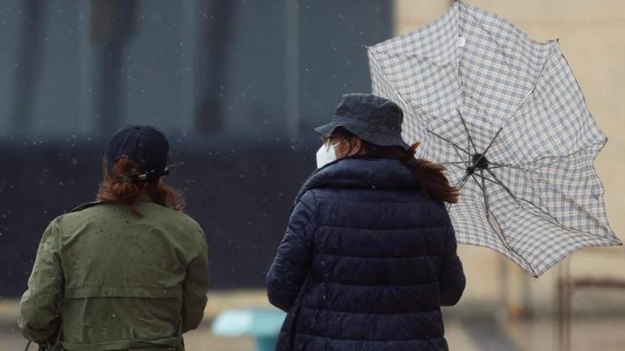 Dos personas tratan de protegerse de la lluvia bajo un paraguas. | K. FORSTERLING/EFE