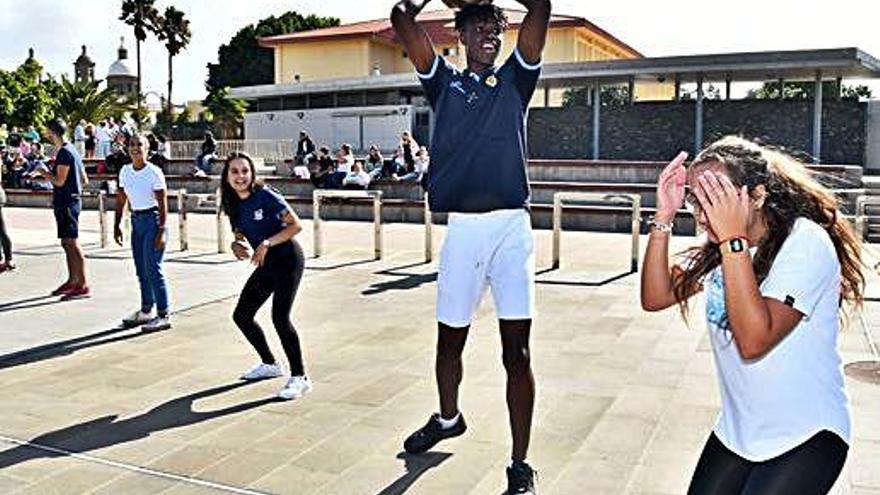 Un jugador de la cantera del Club Baloncesto Gran Canaria y varias jóvenes, entre risas, en una actividad de integración junto al Teatro Auditorio.