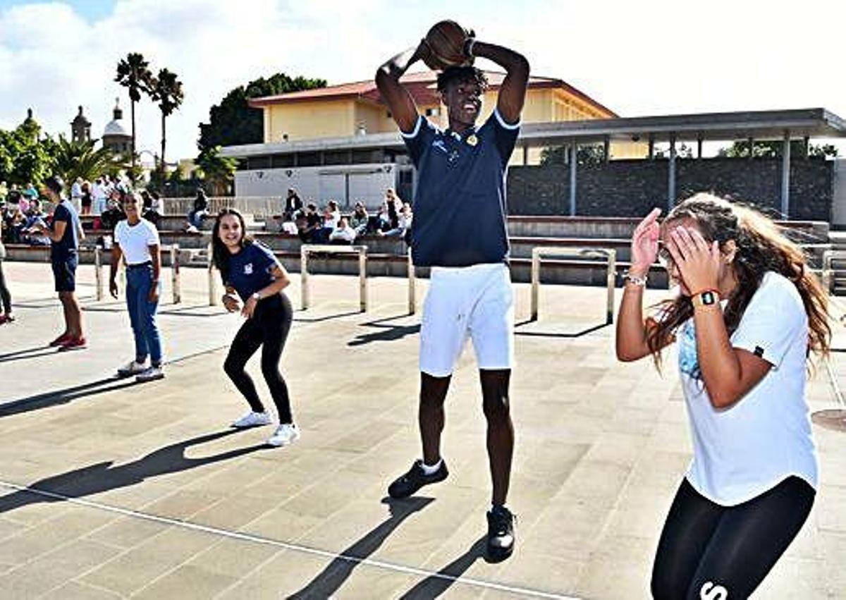 Un jugador de la cantera del Club Baloncesto Gran Canaria y varias jóvenes, entre risas, en una actividad de integración junto al Teatro Auditorio.