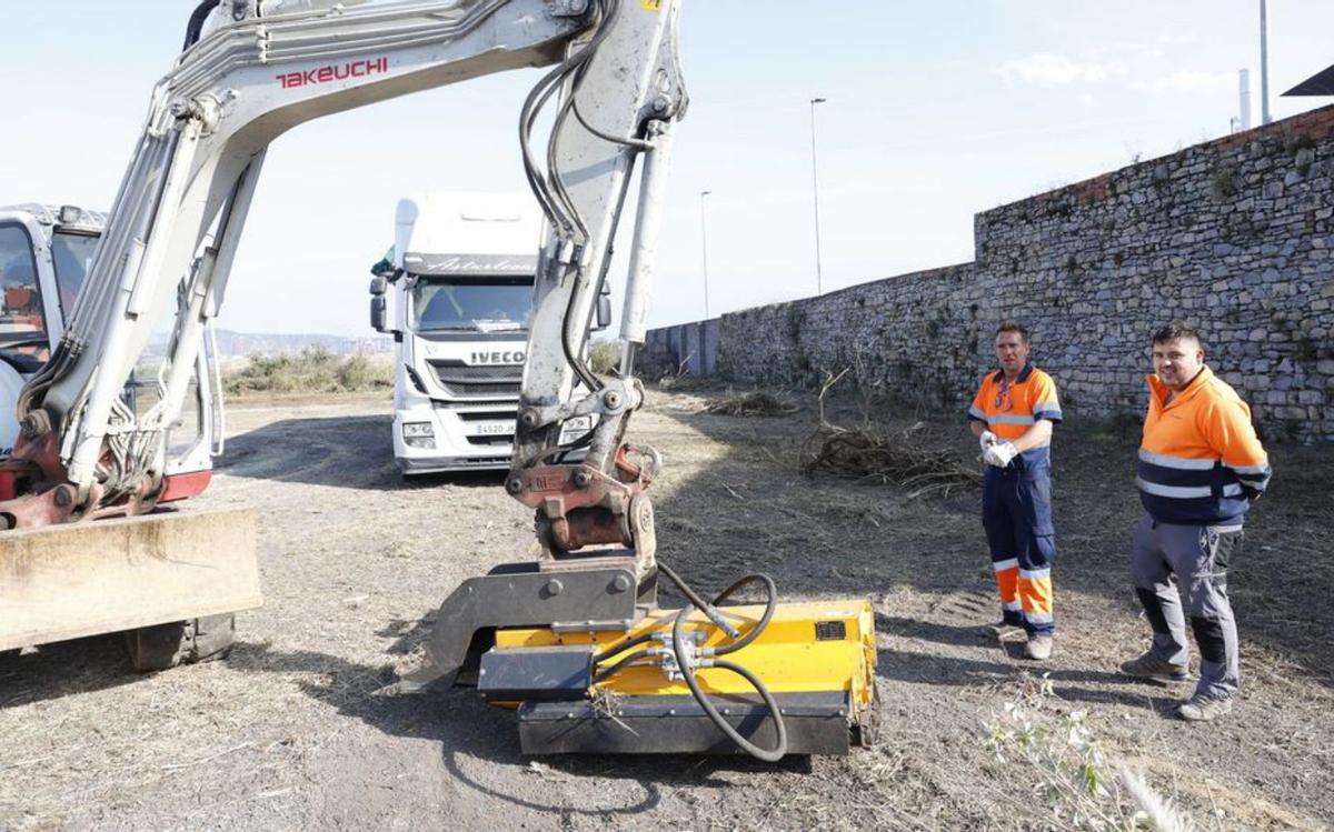Por la izquierda, el operario de la máquina que elimina los rastrojos, Adrián Ogando Corredoira, y el camionero Julio Menéndez Mata, ayer, en la parcela municipal de Naval Gijón. | ÁNGEL GONZÁLEZ