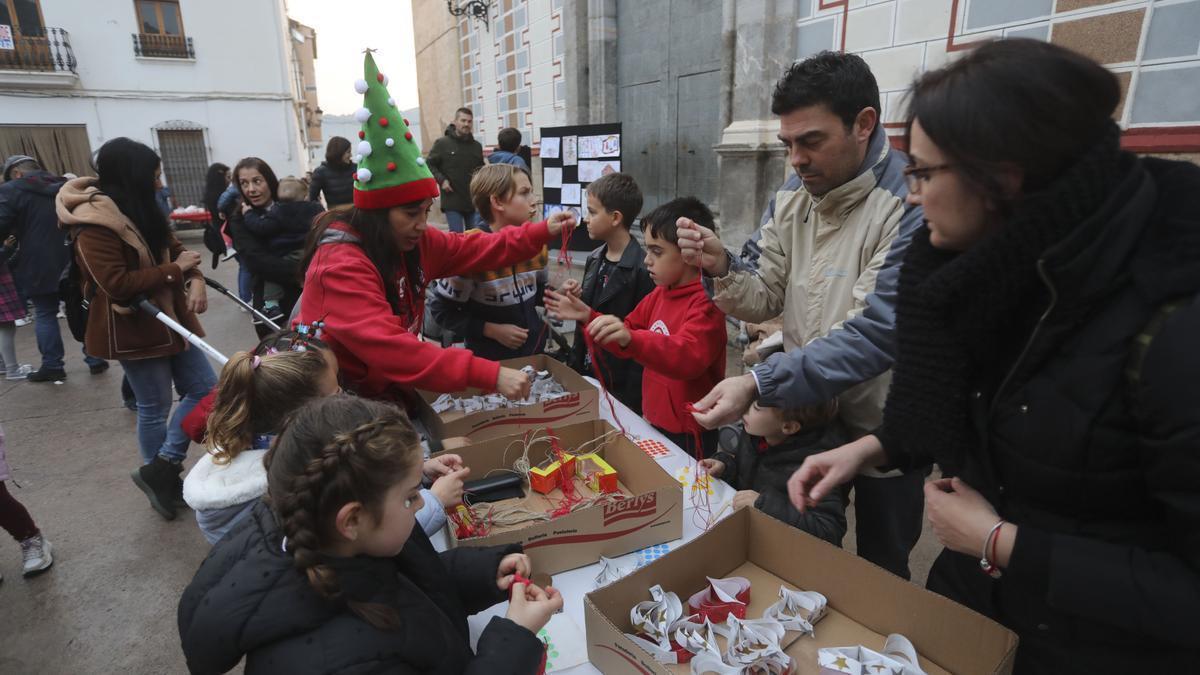 Los niños y las niñas colaboran en la decoración del árbol de Navidad en Petrés.
