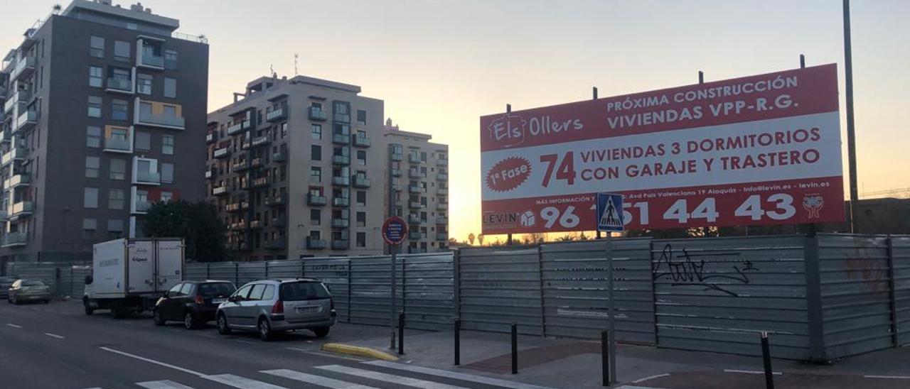 Solar vallado con el cartel de la nueva promoción, junto a otros bloques de viviendas.