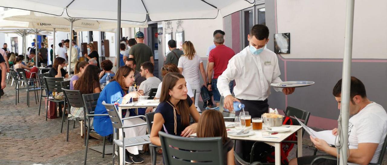 Un joven atiende a clientes sentados en una terraza de bar, en Córdoba.