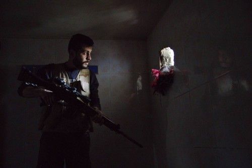Un miembro del Ejército Sirio Libre mira a través de un agujero en un muro en Deir al-Zor