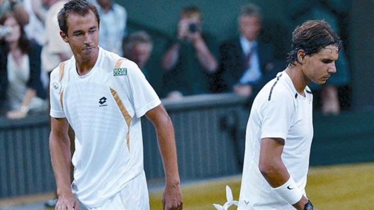 Nadal marcha de la pista tras saludar a su rival, Lukas Rosol, que le eliminó ayer en Wimbledon.