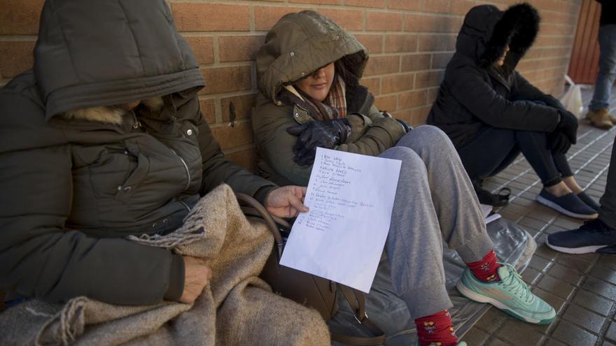 Mujeres migrantes a al espera de la cita previa muestran la hoja donde se apunta el turno.