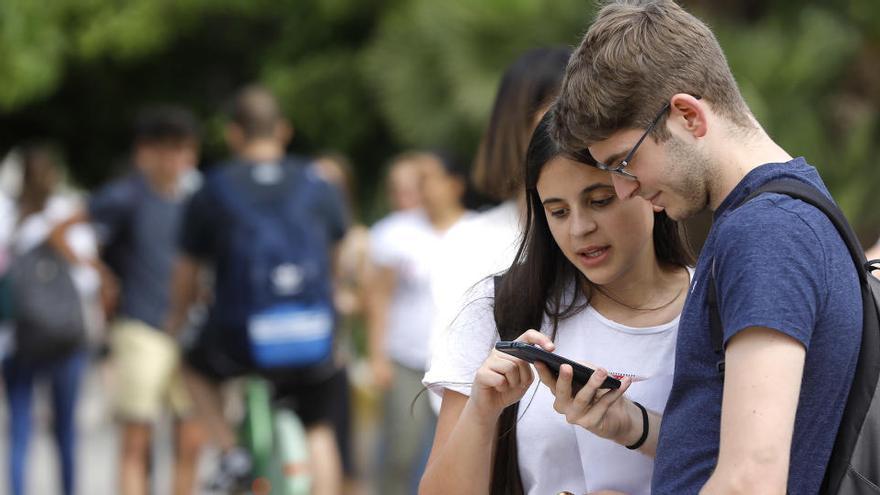 Dos estudiantes miran el móvil tras realizar el examen de Selectividad.