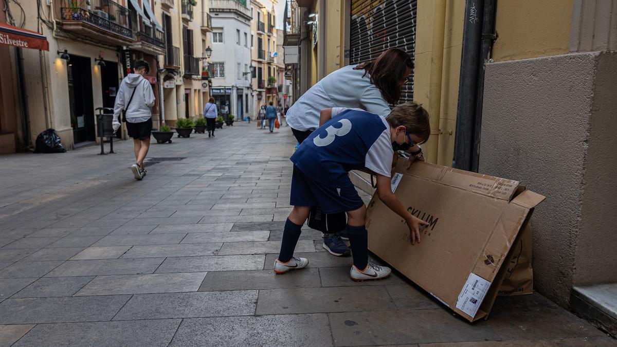 Una madre y su hijo depositan un cartón en la fachada de casa, en Major de Sarrià, el viernes pasado