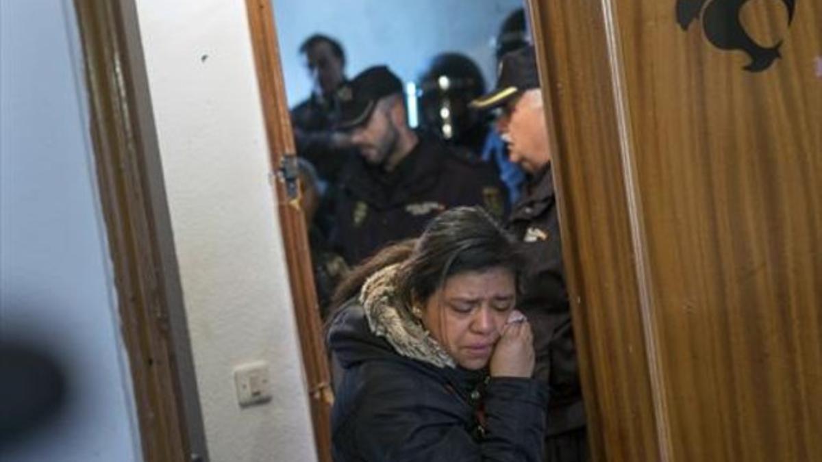 Una mujer abandona llorando la casa ocupada en la que vivía con su familia, tras ser desahuciada por la policía.