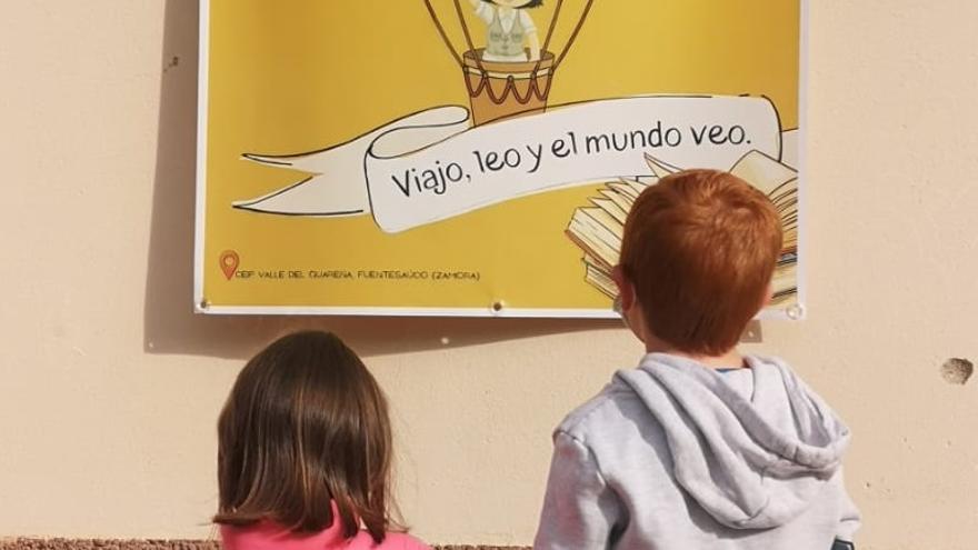 Dos niños observan un cartel de la actividad en el CEIP Valle de Guareña