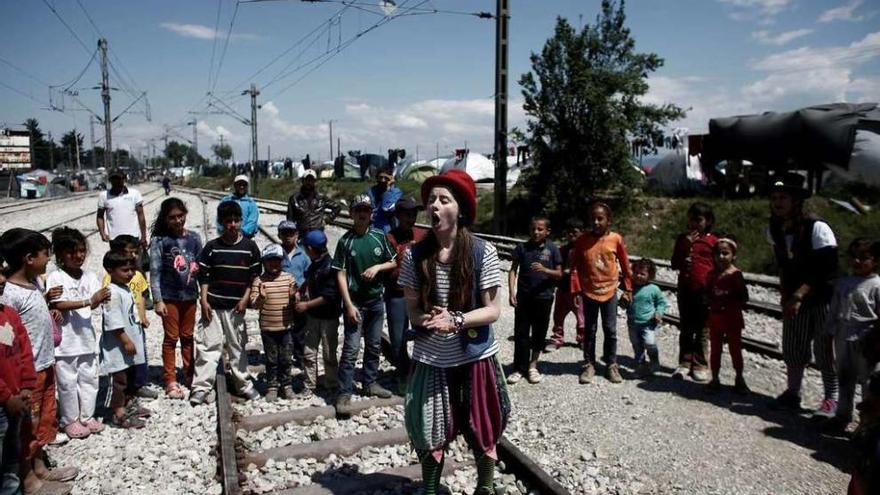 Una joven entretiene a los niños refugiados en el campo de Idomeni disfrazada de payaso.