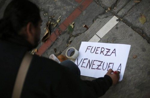 A supporter of Chavez writes a sign reading "Strength Venezuela" outside Venezuela's embassy in Mexico City